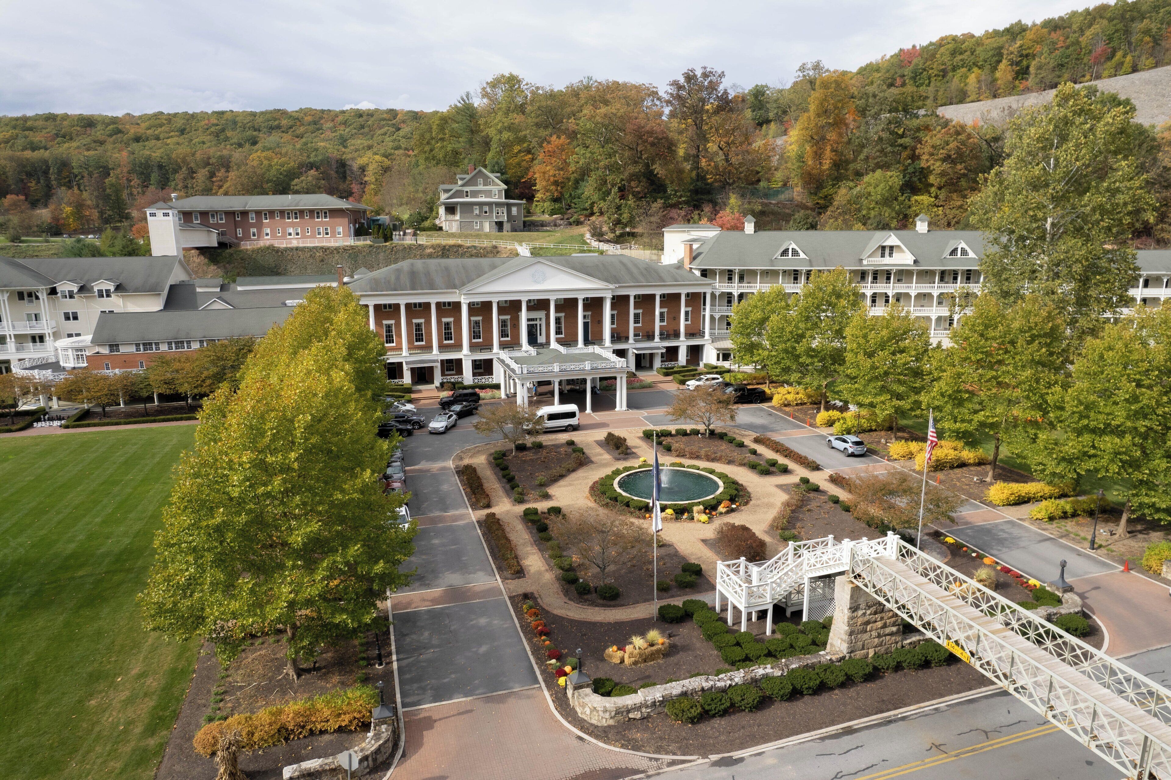 A large, multi-story building with a central courtyard, surrounded by landscaped gardens and a bridge.