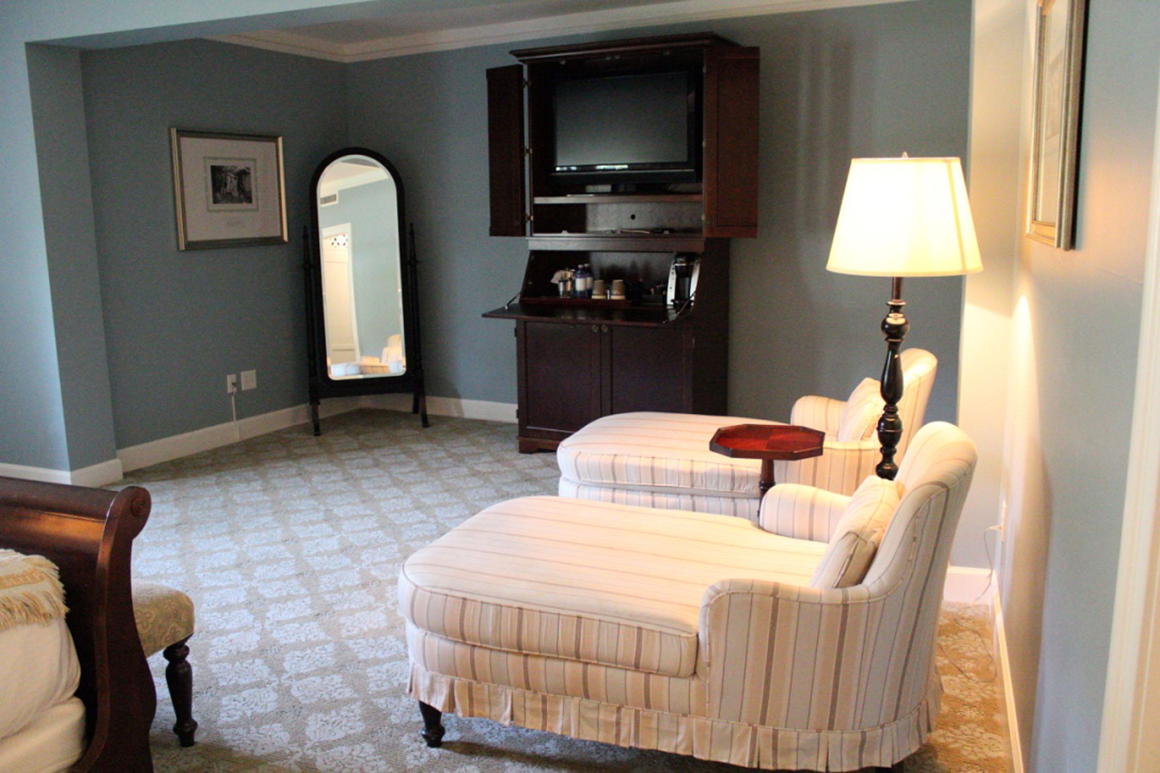 A living room with a sofa, a chair, a TV, and a lamp.