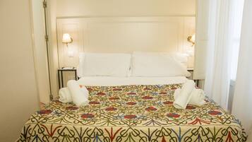 A hotel room with a bed, two bedside lamps, and a patterned bedspread.