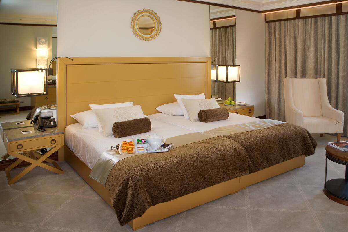 Ein Hotelzimmer mit einem großen Bett, einem Nachttisch mit Lampe, einem Sessel und einem Spiegel an der Wand.