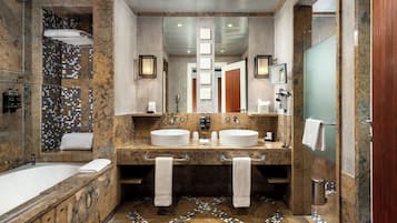 A modern bathroom with two sinks, a large bathtub, and a shower area.