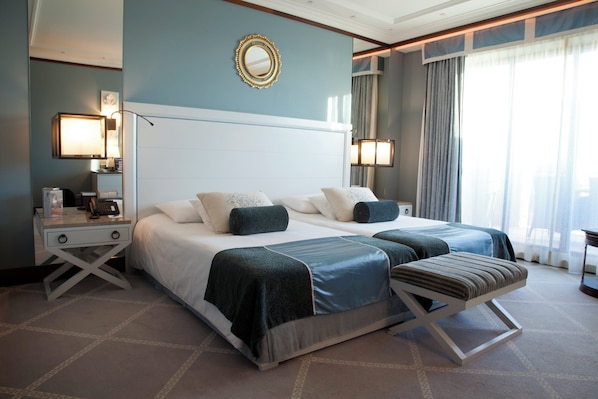 A hotel room with a large bed, two bedside tables, a desk, and a chair. - Grande Real Villa Itália Hotel & Spa - A Leading Hotel of the World (Cascais)