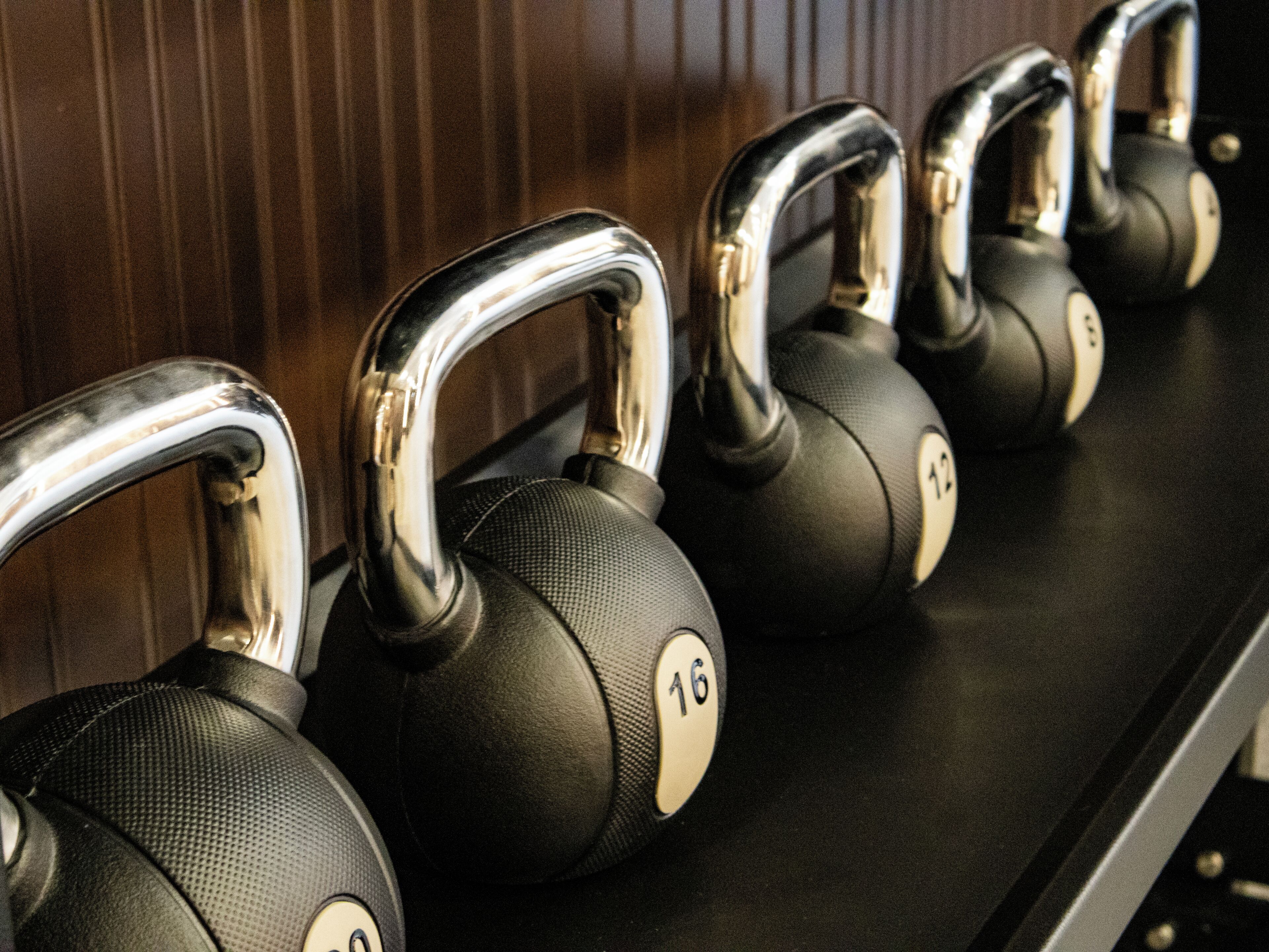 A row of black kettlebells with chrome handles, each marked with a number.