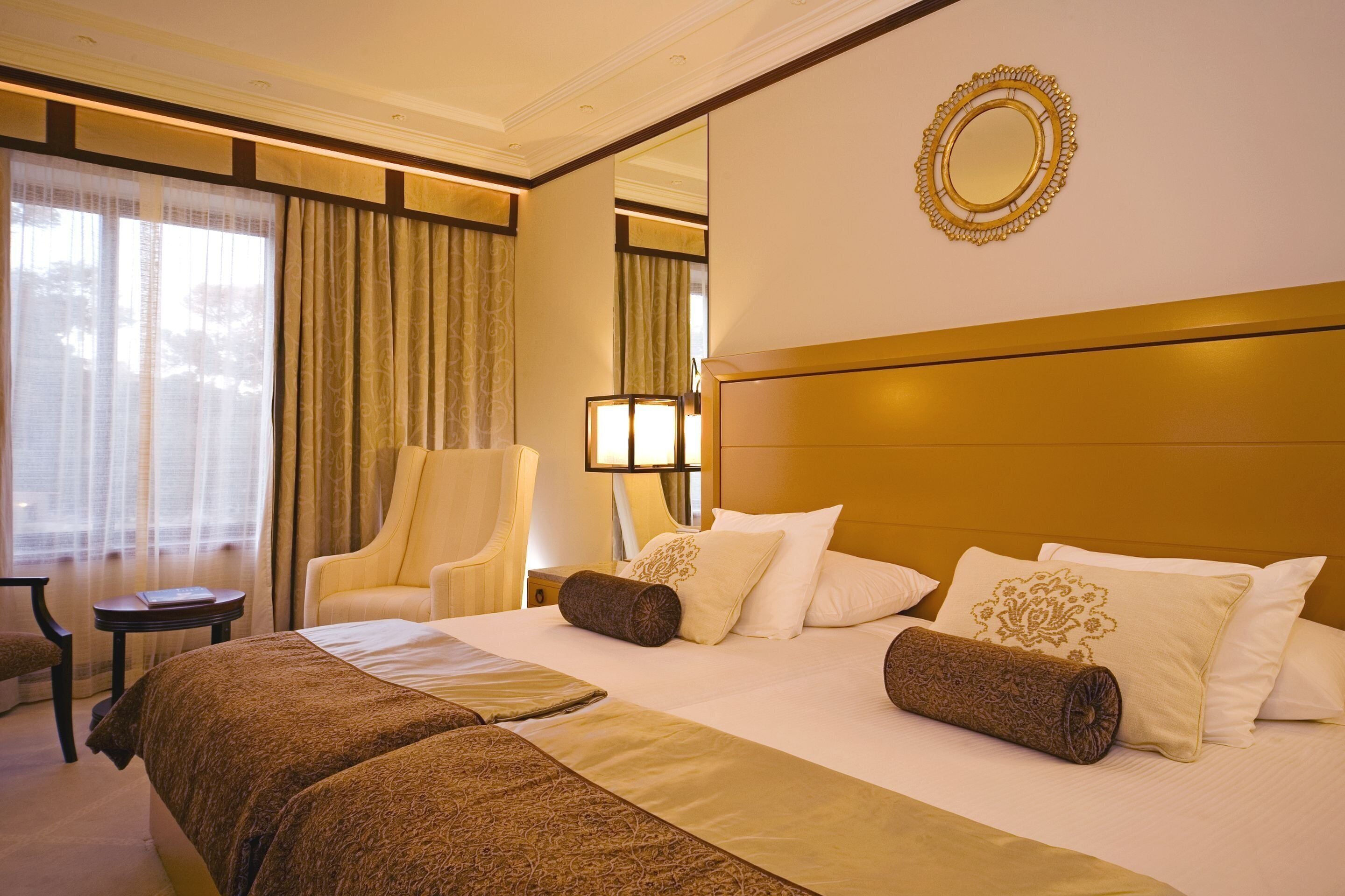 Una habitación de hotel con una cama grande, una silla, una lámpara y un espejo en la pared.