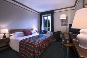 Ein Hotelzimmer mit Bett, Nachttisch, Stuhl, Schreibtisch, Lampe und Fernseher.