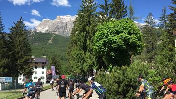 A group of cyclists in a mountainous area with a building in the foreground.