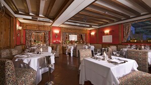 A restaurant with wooden beams, patterned upholstery, and tables set for dining. - Boutique Hotel Villa Blu Cortina (Cortina d'Ampezzo)