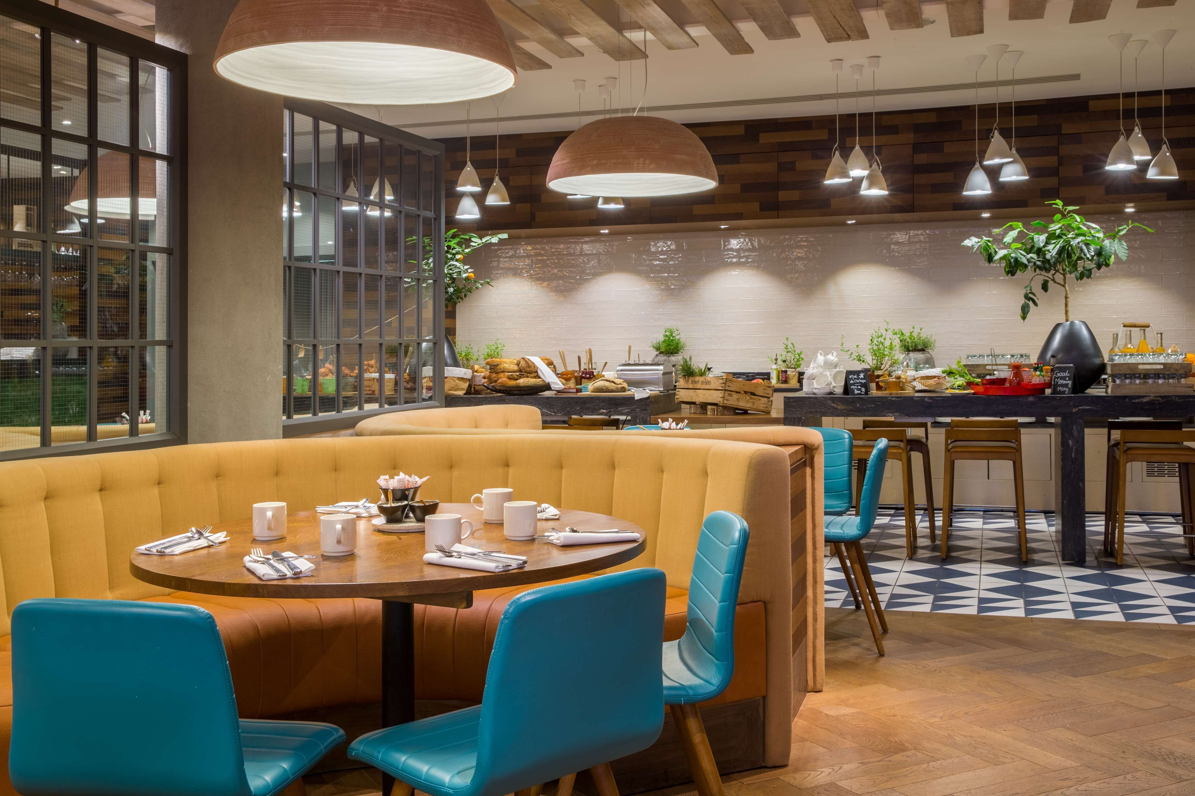 A restaurant with a booth seating area, a counter with a menu, and a plant on the counter.