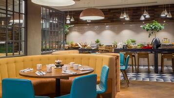 A restaurant with a booth seating area, a counter with a menu, and a plant on the counter.