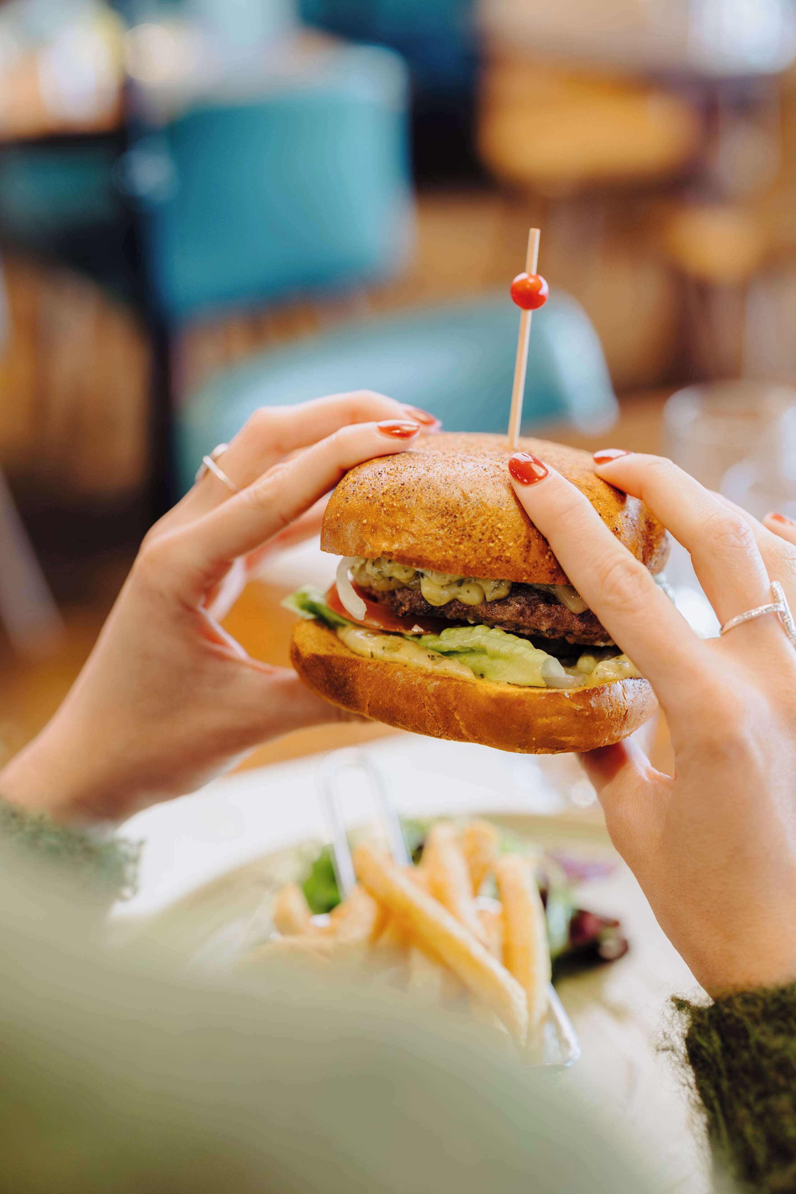 Une personne tenant un hamburger à l'aide d'un cure-dent.