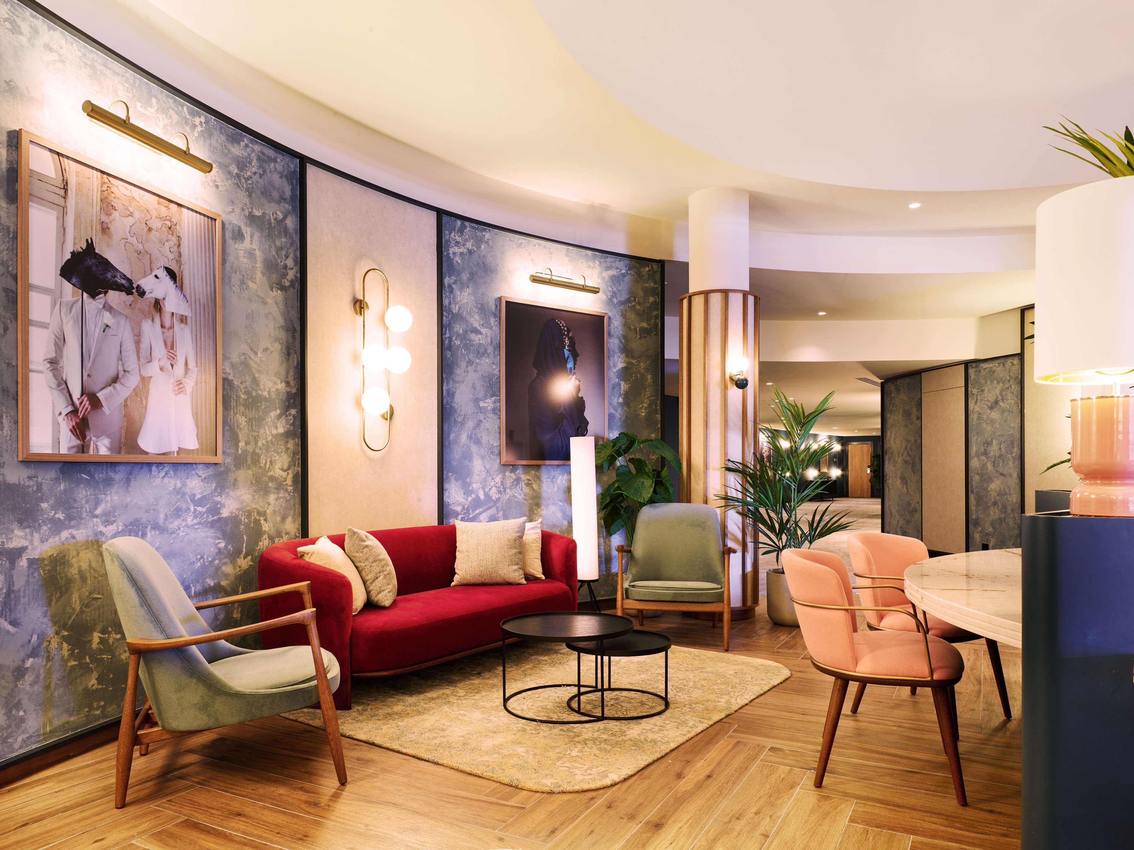 A modern living room with a red sofa, a round coffee table, and a dining area with a marble table and chairs.