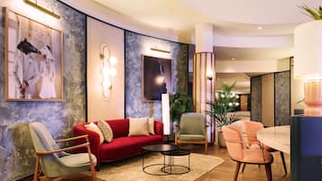 A modern living room with a red sofa, a round coffee table, and a dining area with a marble table and chairs.