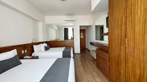 Una habitación de hotel con dos camas, un armario de madera, un espejo y un equipo de aire acondicionado.