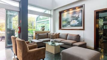 A modern lobby with a sectional sofa, a glass coffee table, and a large painting of water lilies.
