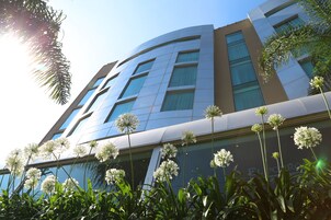 A modern building with a curved facade, large windows, and a reflection of the sky.