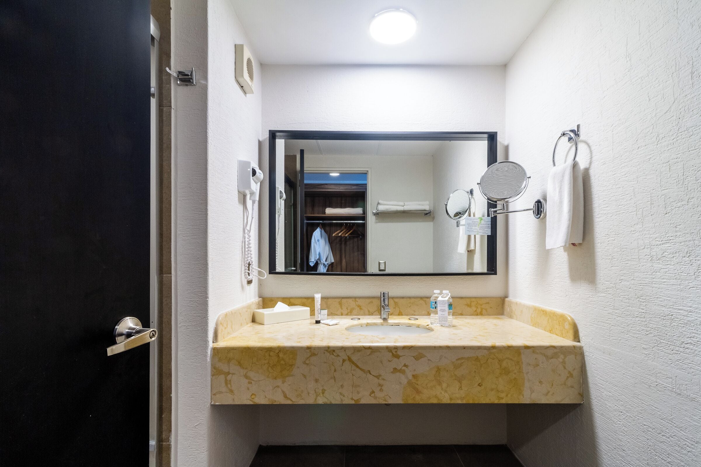 A bathroom with a marble sink, a large mirror, and a towel rack.