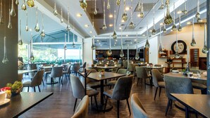 Una cafetería moderna con lámparas colgantes, mesas de madera y asientos cómodos.