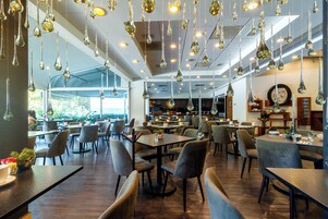 Una cafetería moderna con lámparas colgantes, mesas de madera y asientos cómodos.