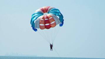 Una persona practica parasailing sobre el océano con un paracaídas colorido.