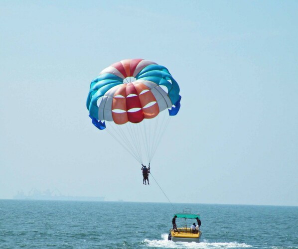 A person parasailing over the ocean with a colorful parachute. - Santana Beach Resort (Candolim)