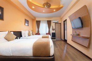 Une chambre d’hôtel avec deux lits, un téléviseur fixé au mur et un luminaire au plafond.