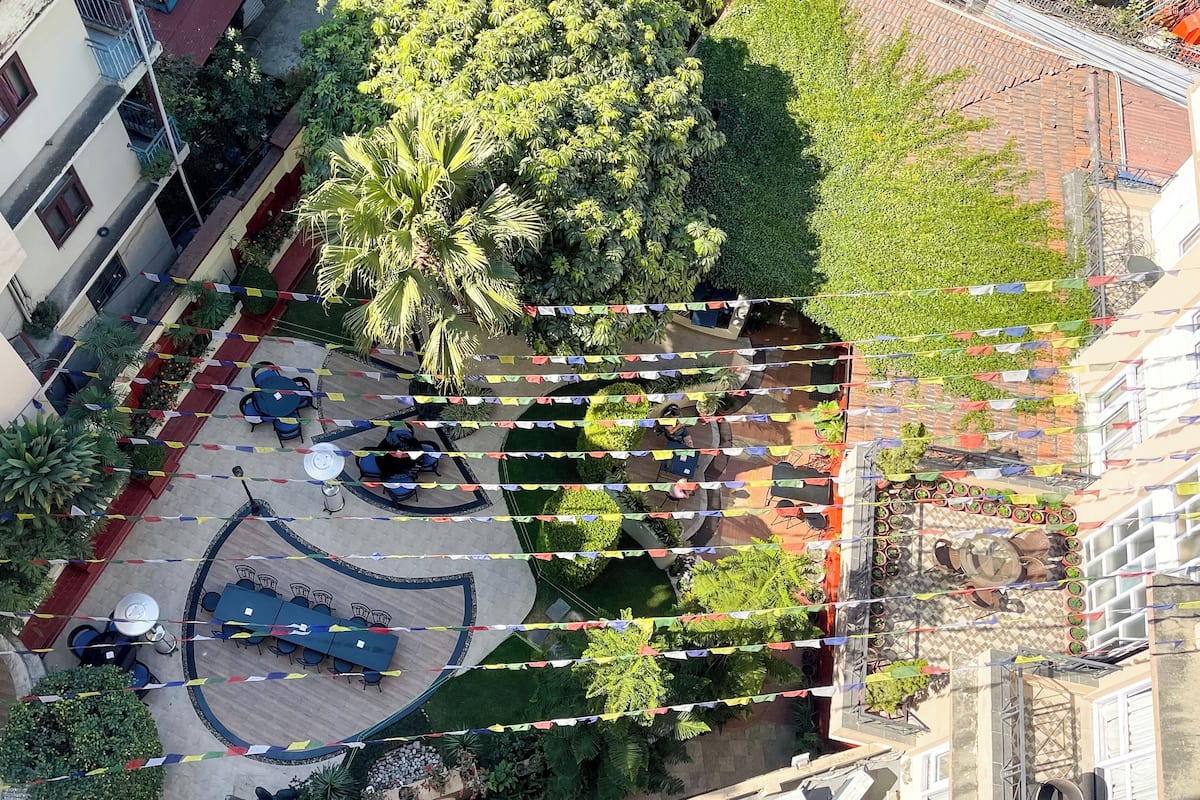 An aerial view of a courtyard with outdoor seating, surrounded by greenery and buildings.