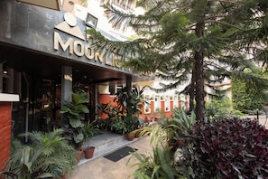 L’entrée d’un hôtel, avec une enseigne indiquant « MOUNTAIN » et une variété de plantes en pot devant.