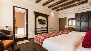 Habitación de hotel con una cama de madera, un escritorio con una silla y un espejo grande.