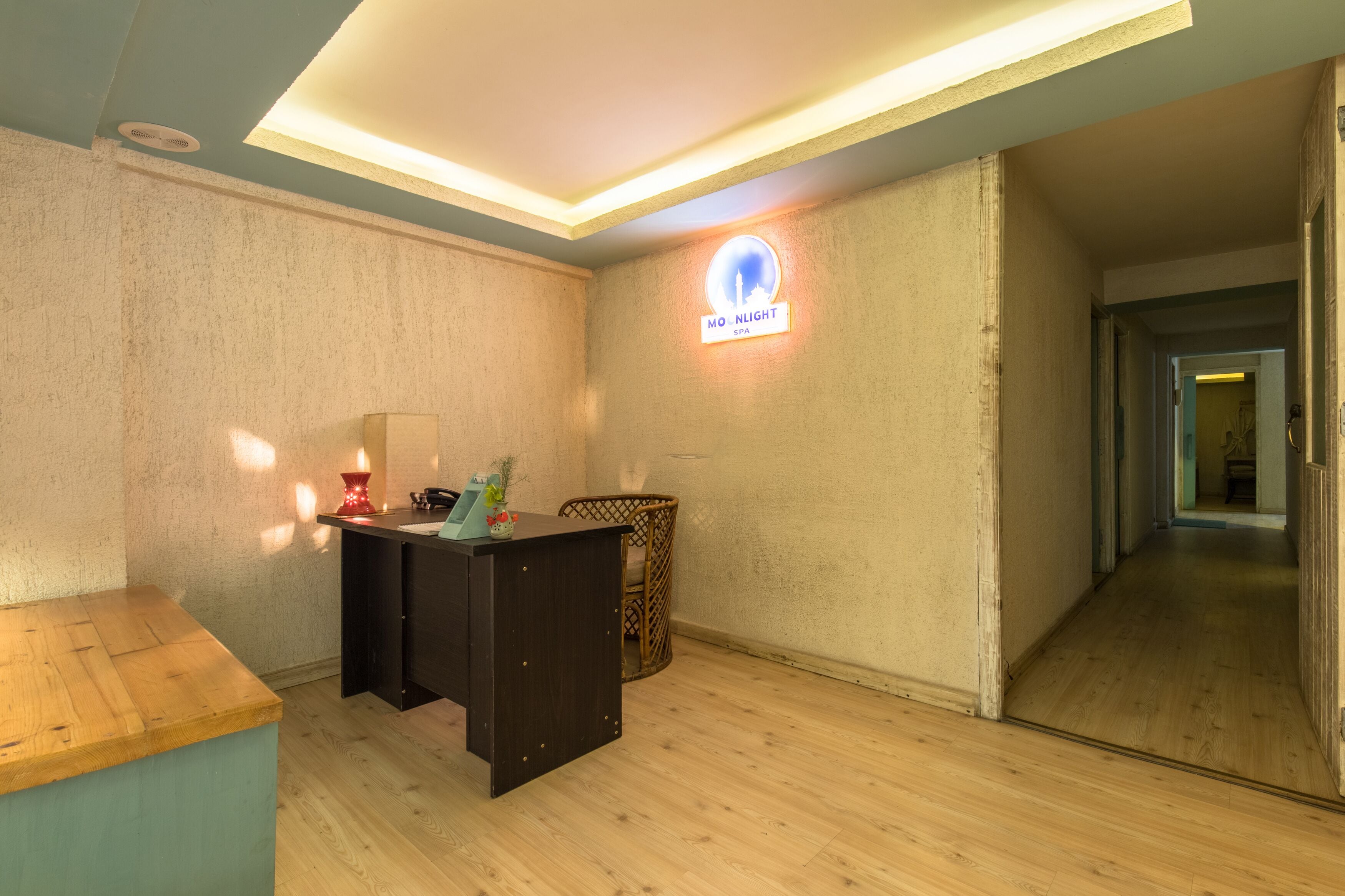 A spa room with a reception desk, a wall-mounted sign, and a wooden floor.