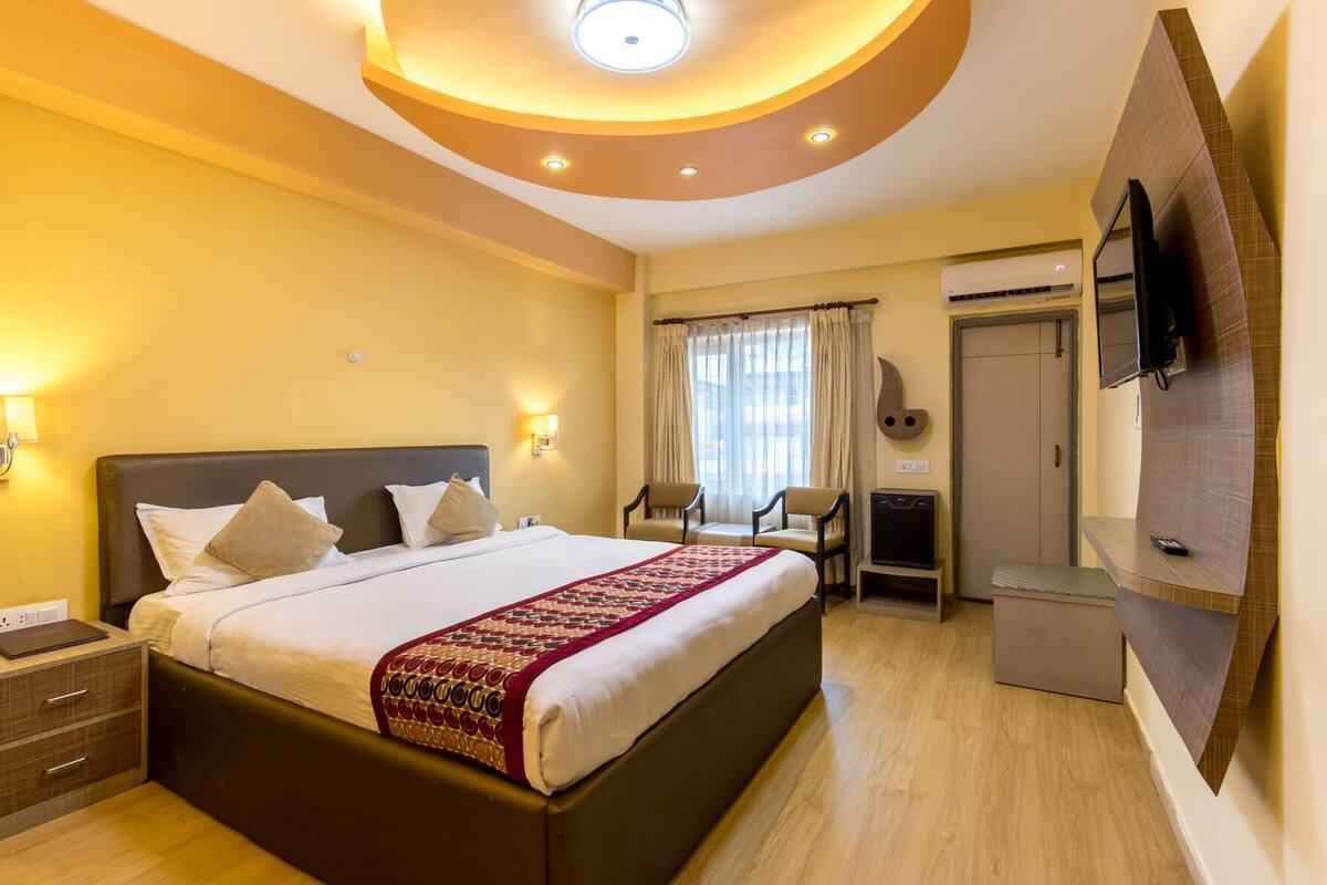A hotel room with a large bed, a desk, a TV, and a wardrobe.