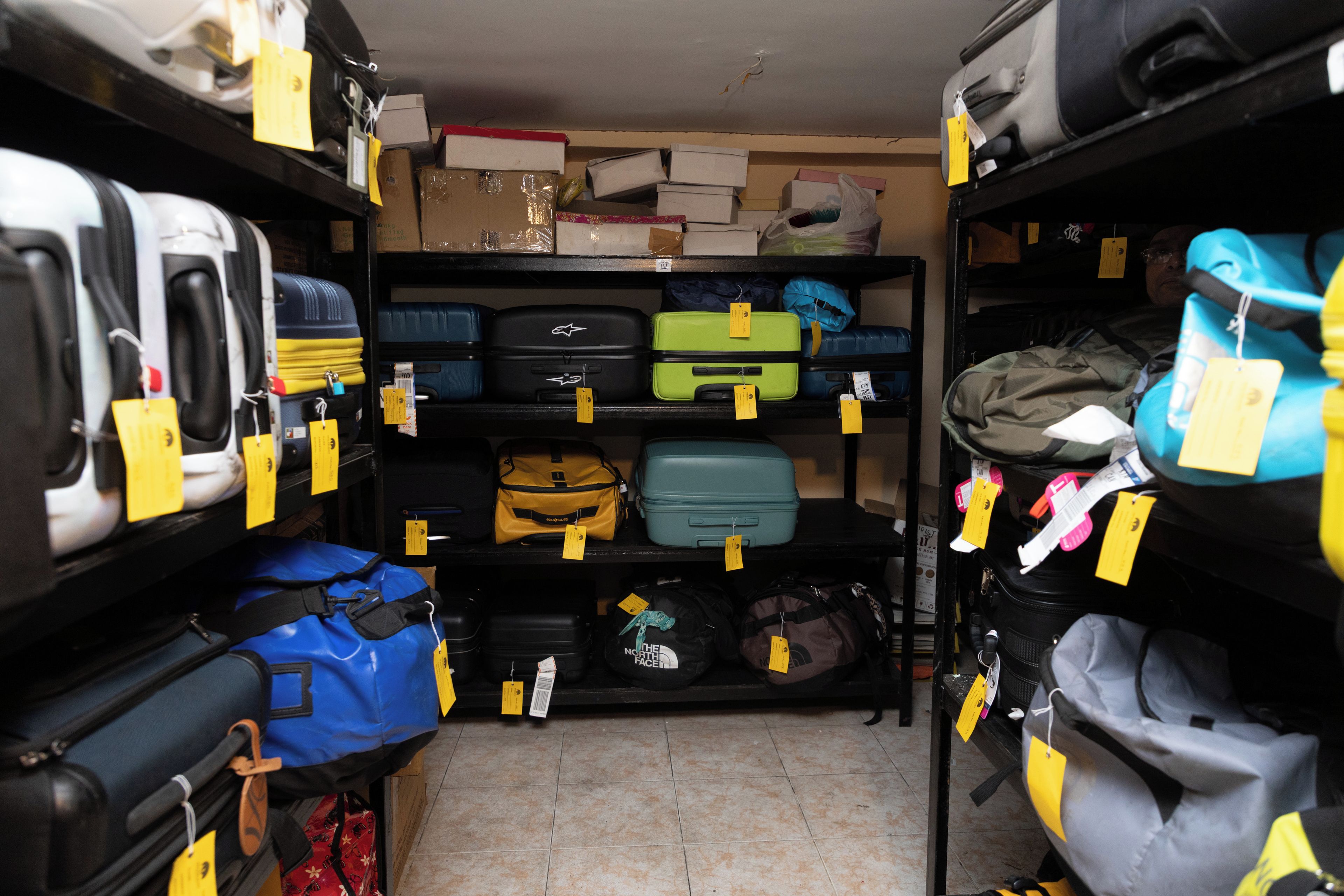 A storage room with shelves containing various bags and suitcases.