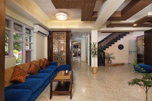 A modern hotel lobby with a blue sofa, a wooden coffee table, a decorative screen, and a staircase. - Hotel Moonlight (Kathmandu)