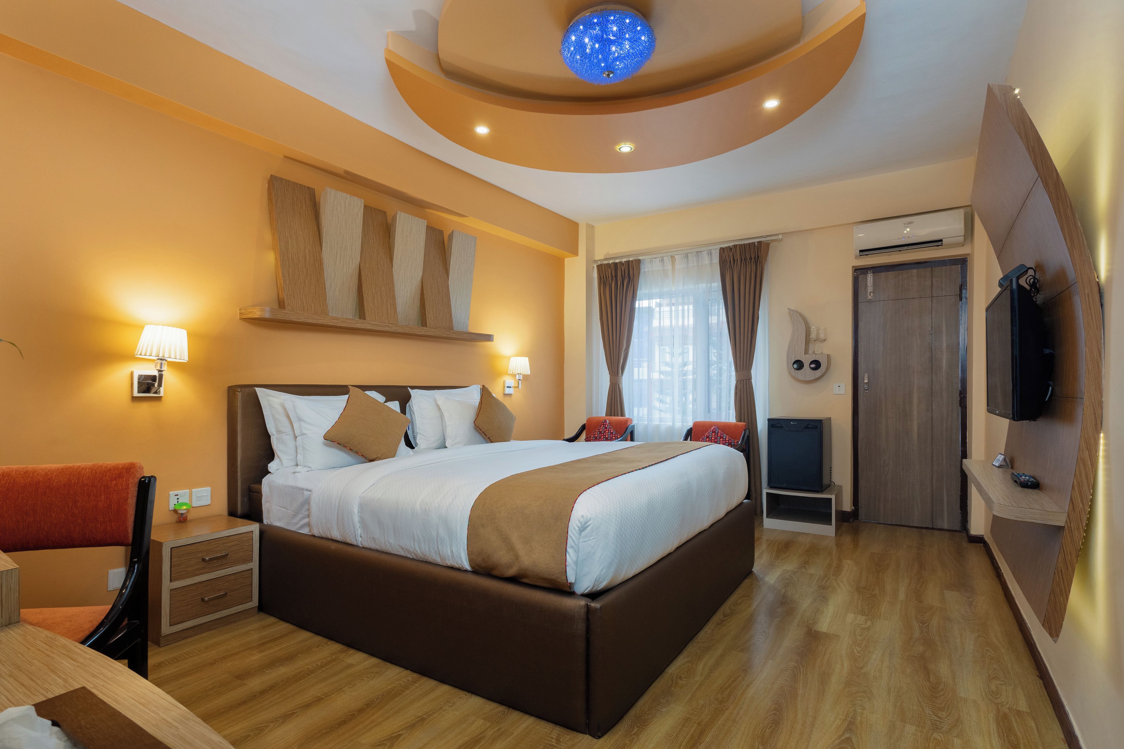 Habitación de hotel con una cama grande, mesitas de noche, un escritorio, televisor y un armario.