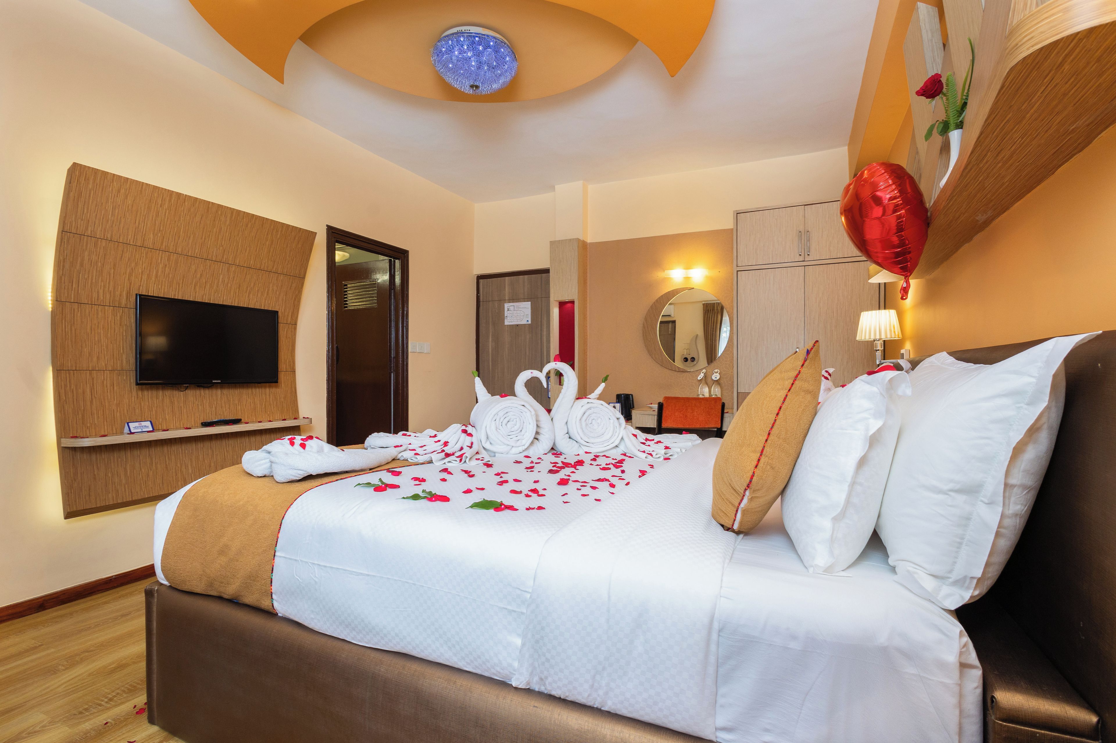 Una habitación de hotel con una cama, un televisor, un espejo y un globo rojo.
