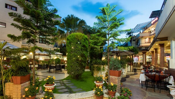 A courtyard with a central garden, outdoor seating, and a restaurant area.
