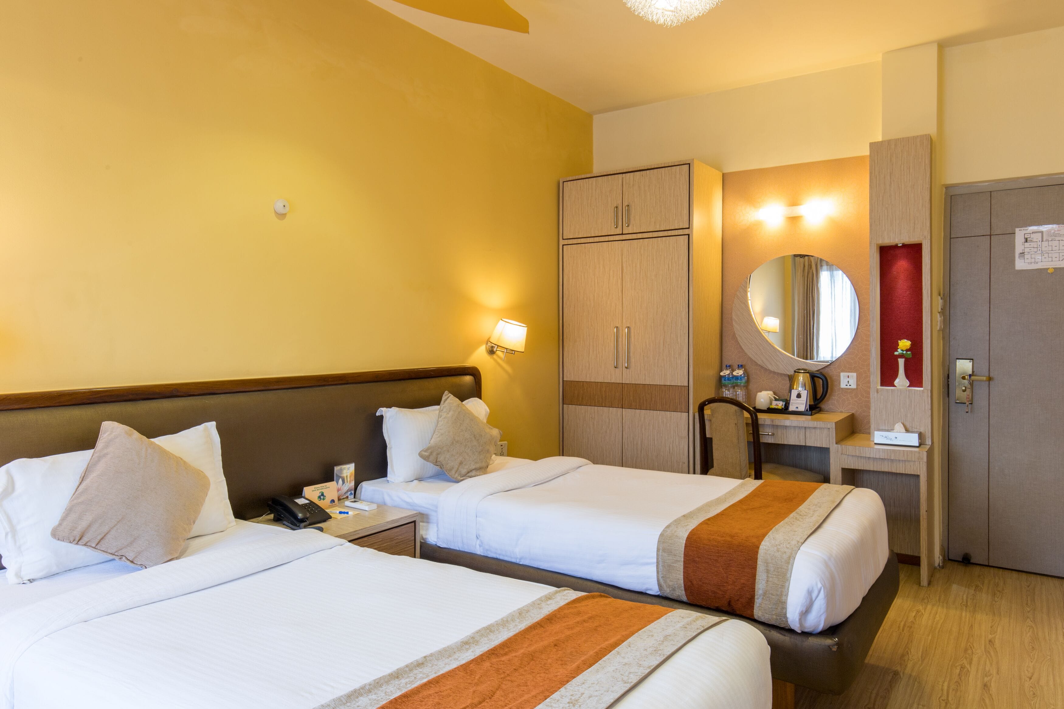 Une chambre d’hôtel avec deux lits, un bureau, un miroir et une armoire.