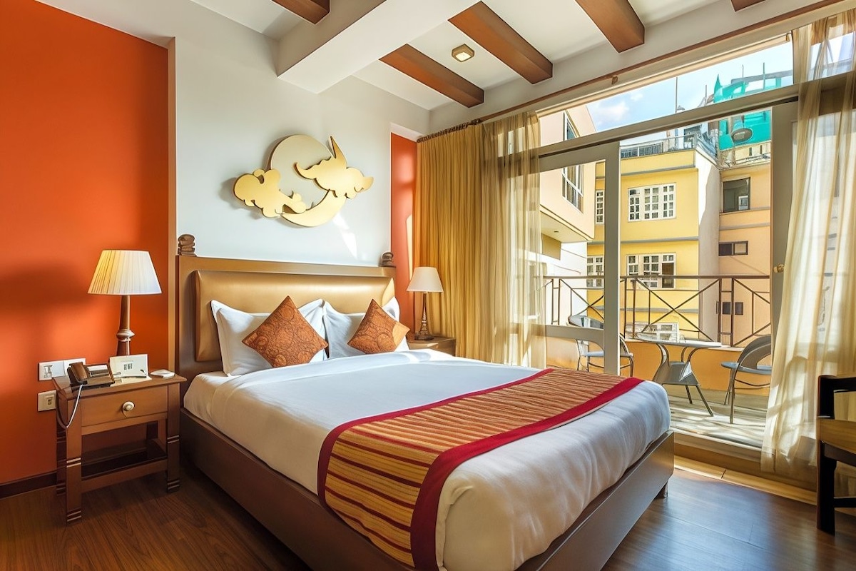 A hotel room with a large bed, a nightstand, a lamp, a wall clock, and a view of the outside balcony.