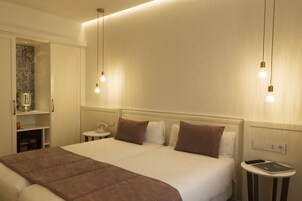 Una camera d'hotel con un letto grande, due comodini, un tavolino e una lampada a parete.