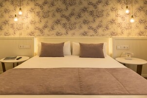 A double bed with a headboard, two bedside tables, a bedside phone, and a patterned wallpaper.