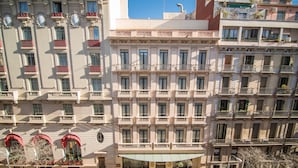 Un hotel de varios pisos con balcones, una entrada central con toldo verde y un cielo azul despejado.
