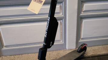 A black electric scooter parked indoors with a sign offering a discount.