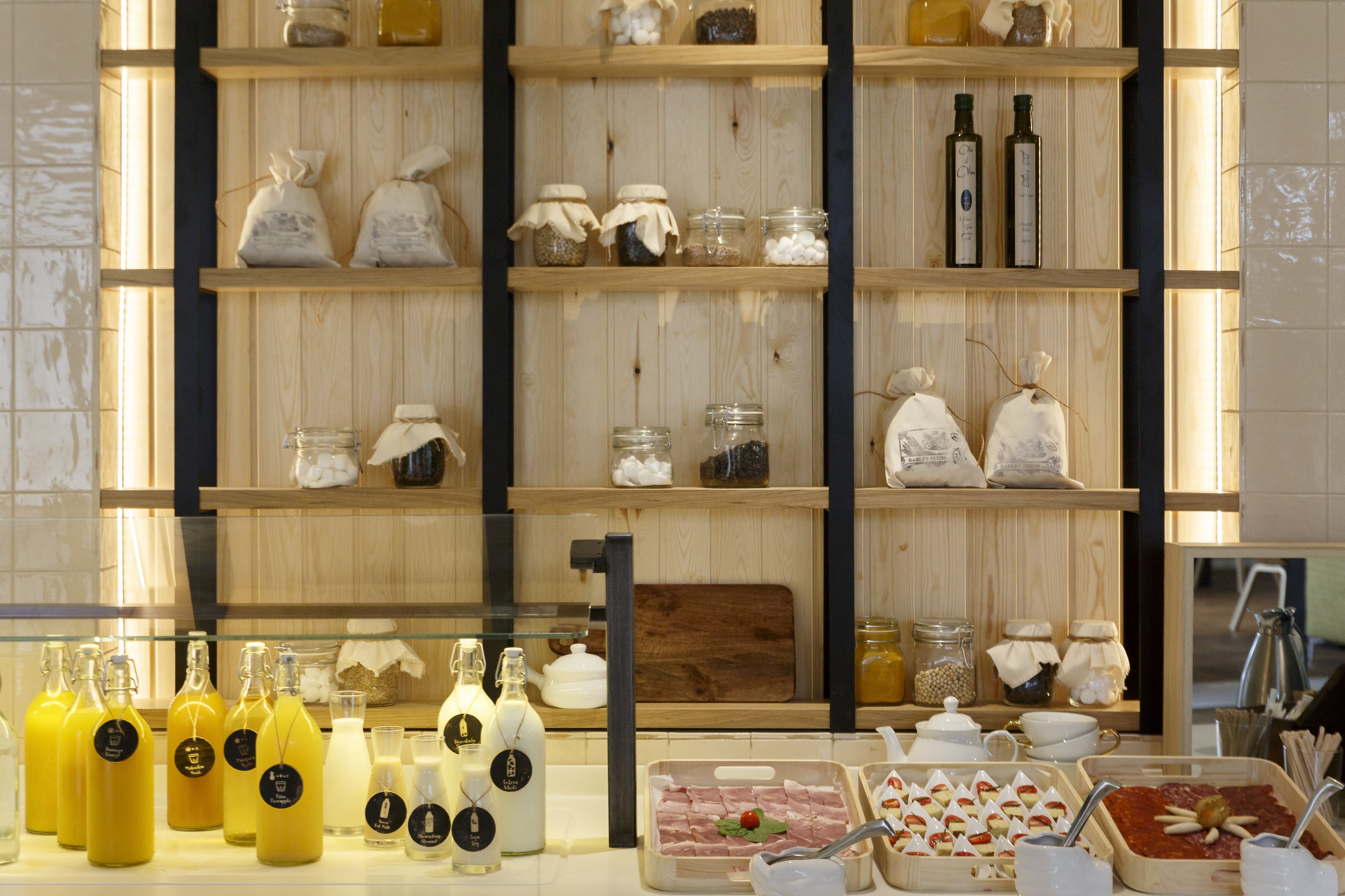 A display of food items and beverages in a store with wooden shelves and glass containers.