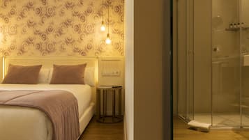 Habitación de hotel con cama, mesita de noche y zona de ducha.