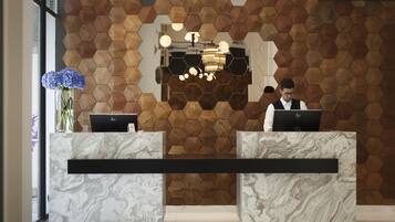 Un mostrador de recepción con encimera de mármol y una pared de madera hexagonal detrás.