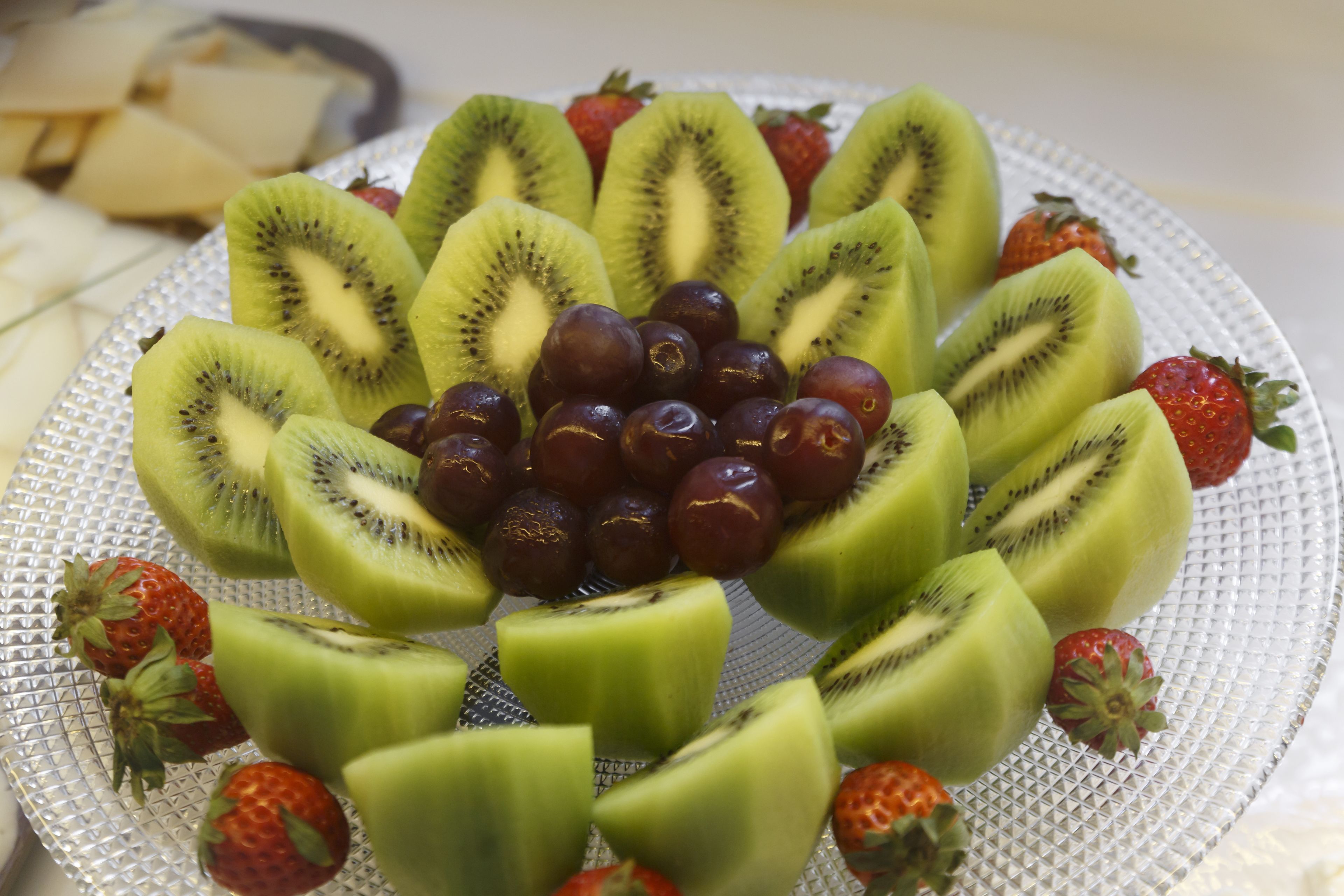 Un piatto con kiwi a fette e uva disposti a cerchio.