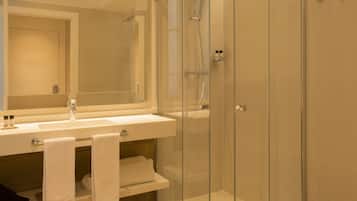Un baño moderno con ducha de vidrio, un lavabo con espejo y un perchero para toallas.