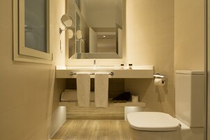 Ein modernes Badezimmer mit Toilette, Waschbecken, Spiegel und Handtuchhalter.