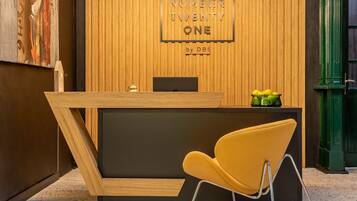Un mostrador de recepción con un panel de madera, una obra de arte enmarcada y una silla moderna.