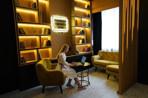 Een moderne kamer met een boekenkast, een laptop en een gele bank.