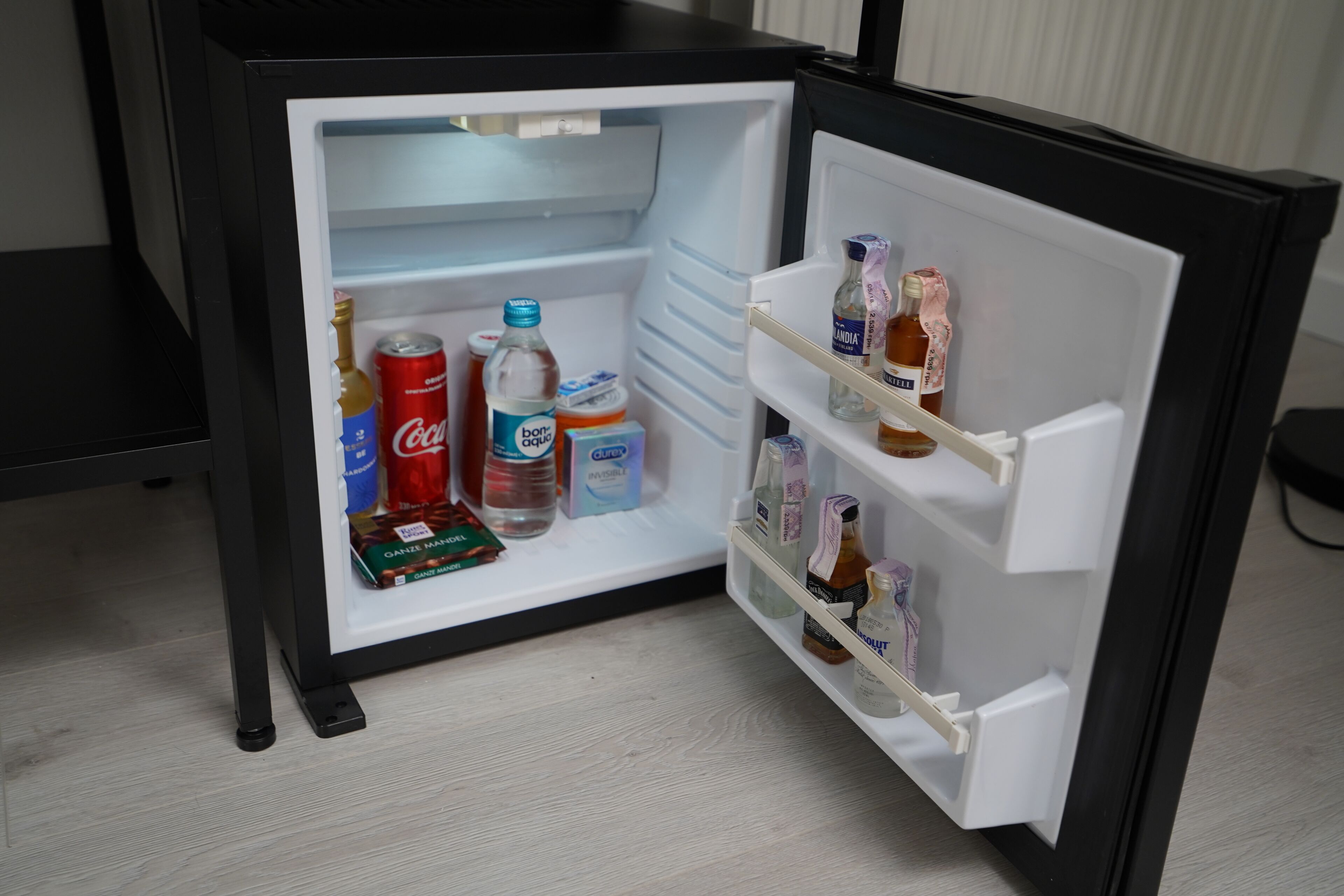 Un réfrigérateur avec des étagères contenant diverses boissons et denrées alimentaires.